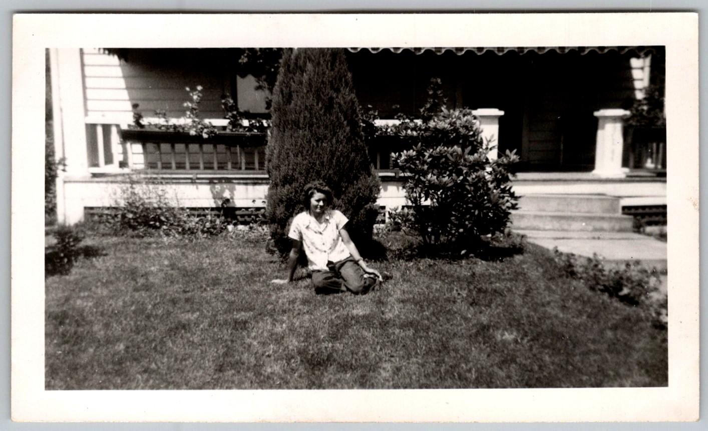 Vtg B&W Snapshot Woman Sitting On Lawn House Porch Large Evergreen Tree 1949
