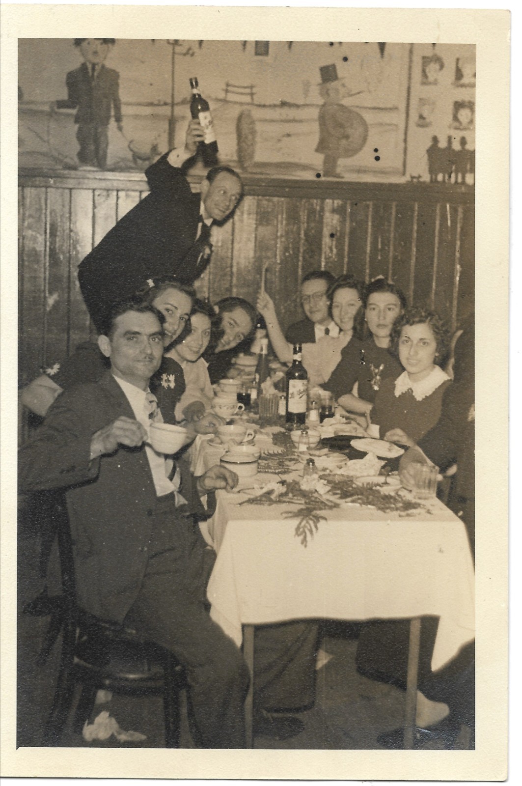 vintage photo family men women restaurant man standing holding wine bottle