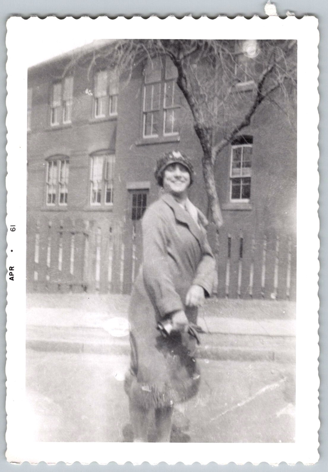 Vtg B&W Snapshot Smiling Woman Coat Hat Brick Building Apr 1961 Photo